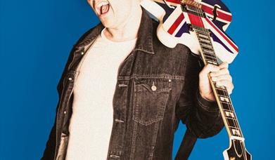 Marc Burrows poses with a union jack guitar over his shoulder