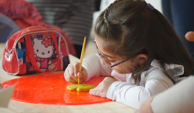 A child decorates a biscuit.