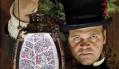 Man in a top hat holding a lamp