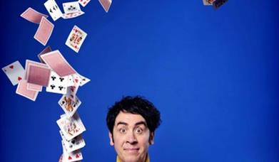 Image shows Pete Firman throwing cards into the air
