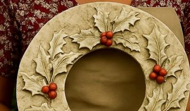 This picture shows a lady holding a Christmas wreath cast