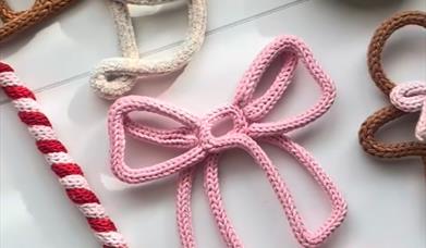 The picture shows Christmas decorations made from wool including a bow and candy canes