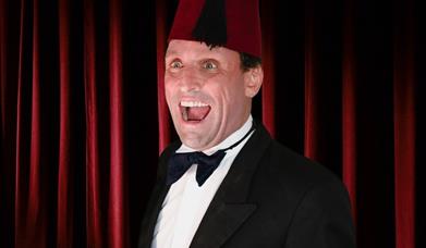 Image shows actor dressed as Tommy Cooper.