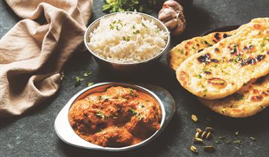 A delicious looking curry with rice and naan bread.