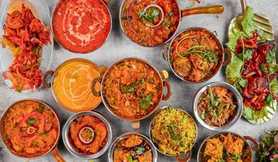 Multiple bright curries against a grey background.