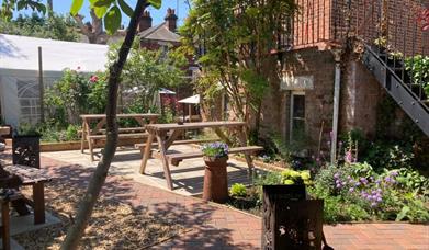 A bright, open beer garden with wooden tables and a path.